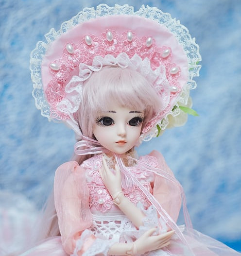 A doll in a pink frilly bonnet and pink dress looks sad and worried, staring into the distance.