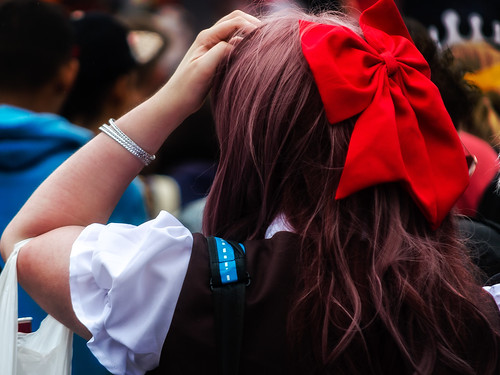 Schoolgirl with large red bow i nher hair, seen from the back.