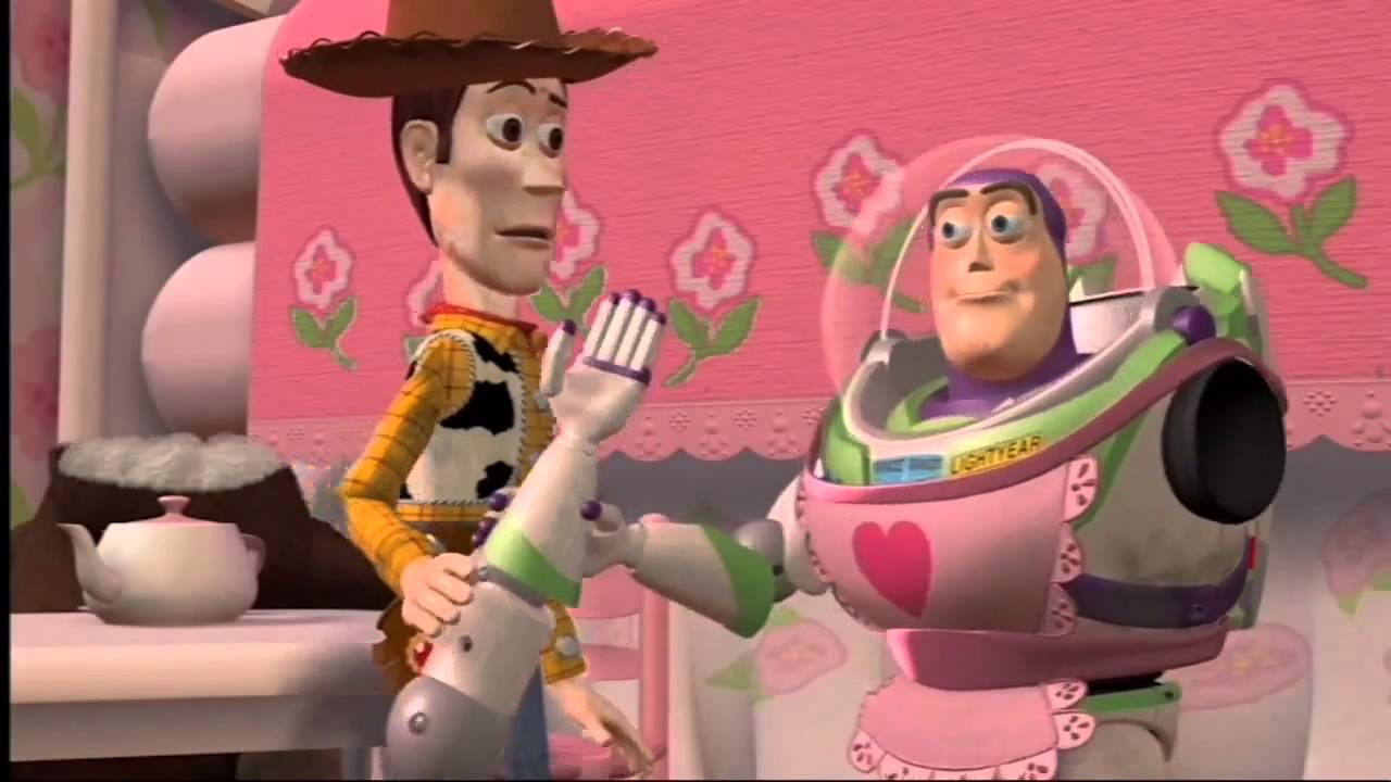 Buzz Lightyear the astronaut toy is dressed in a pink apron as Mrs Nesbitt in Toy Story. Woody the Cowboy looks on with concern.