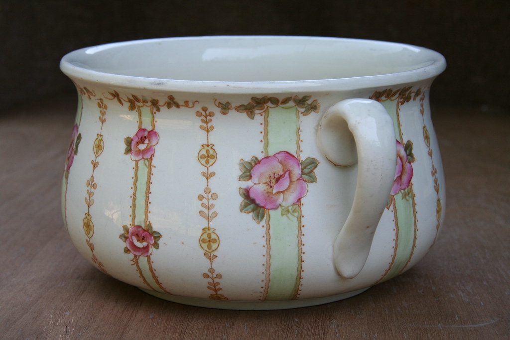 A ceramic chamber pot with a floral design.