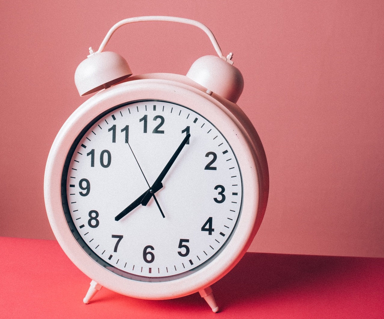 A pink alarm clock set to just past 8.