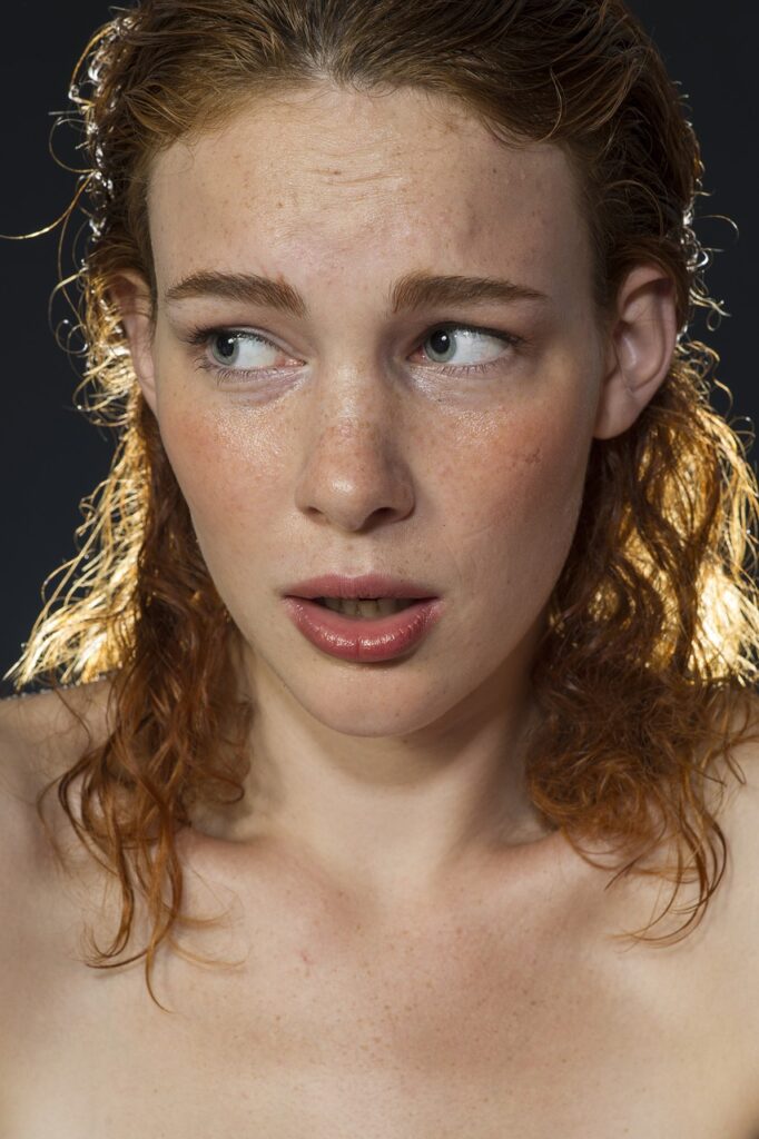 Anxious red-haired woman with wet hair and no clothes.