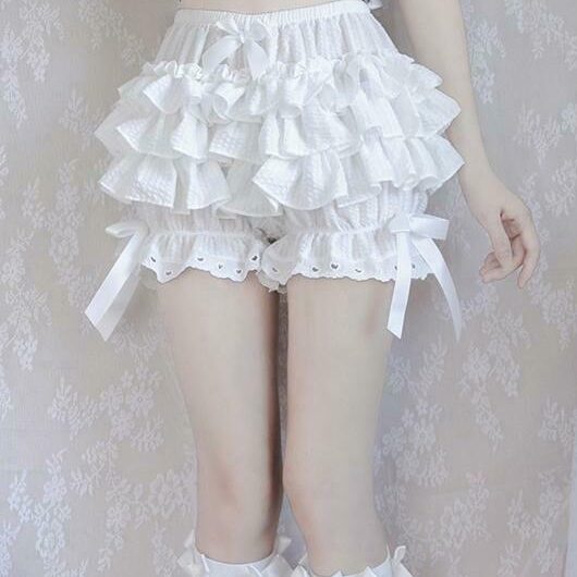A woman's lower body dressed in white ruffled pumpkin bloomers.