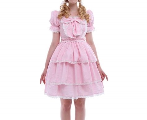 A woman in a babyish pink dress with ruffled skirts, puff sleeves and a bow. Her blonde hair is in two curly bunches.