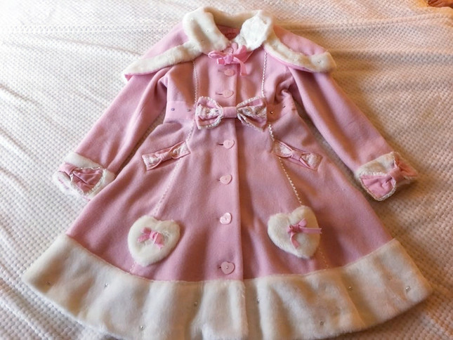 A pink Sweet Lolita style princess coat with white fluffy cuffs and trim, heart pockets and cute bows all over.