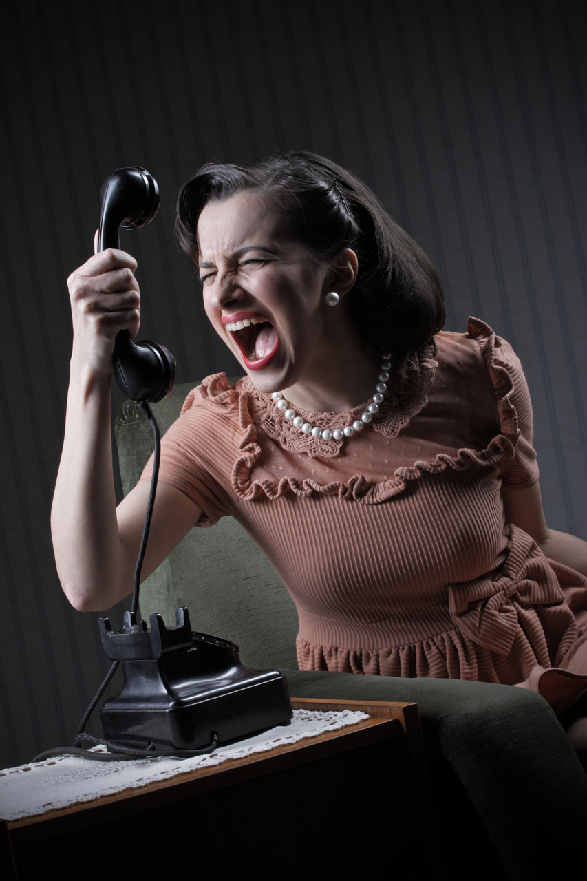 Angry woman screaming at retro phone, 1950 style