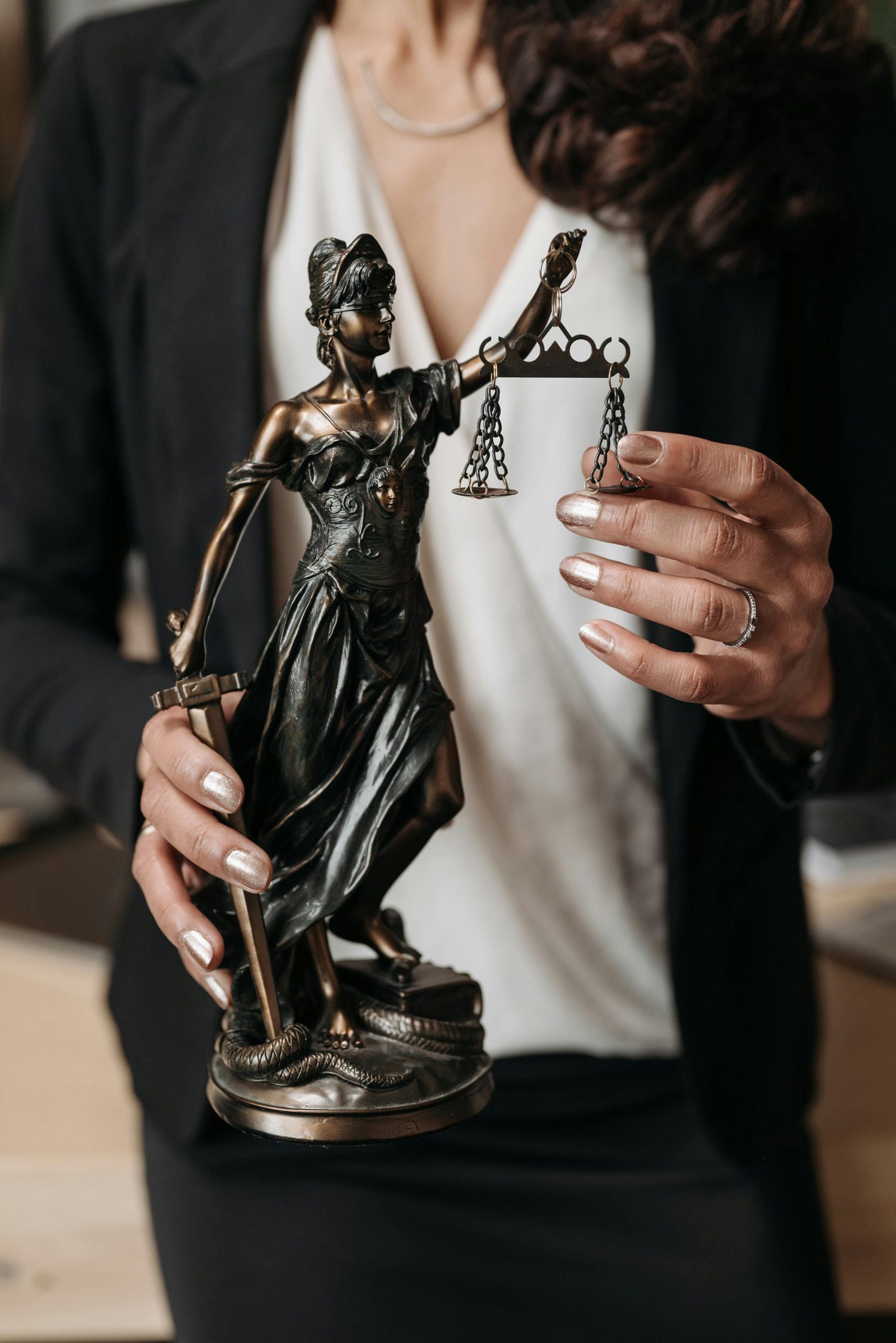 A business woman holds a statue of Lady Justice.