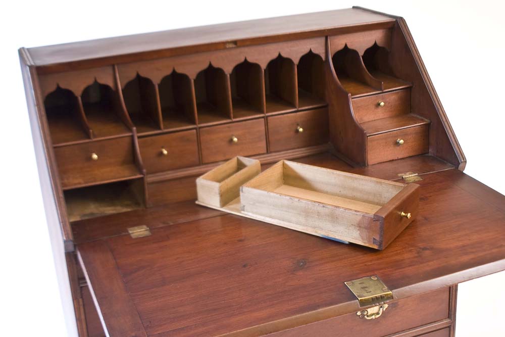 An antique bureau with a revealed hidden drawer.